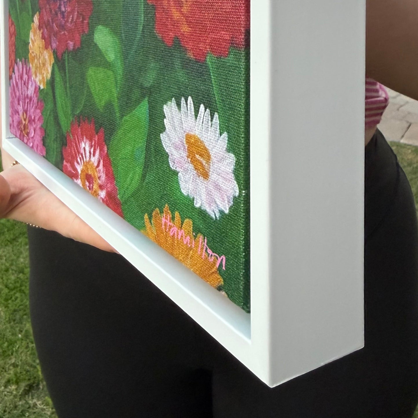 A side view of Julie Hamilton’s white gallery framed canvas print of a hummingbird with colorful zinnias