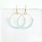 Gold hoop earrings with light blue beads on a white background by Phoenix artist Julie Hamilton 