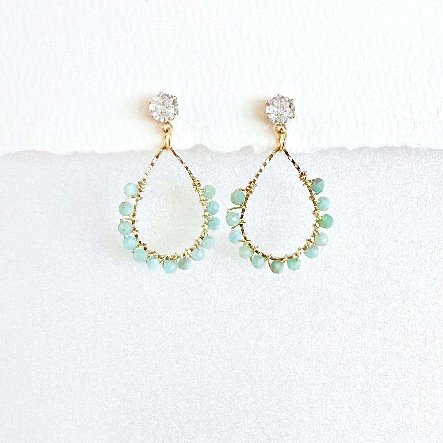 Gold teardrop earrings wrapped with Aquamarine beads on a white background by artist Julie Hamilton 
