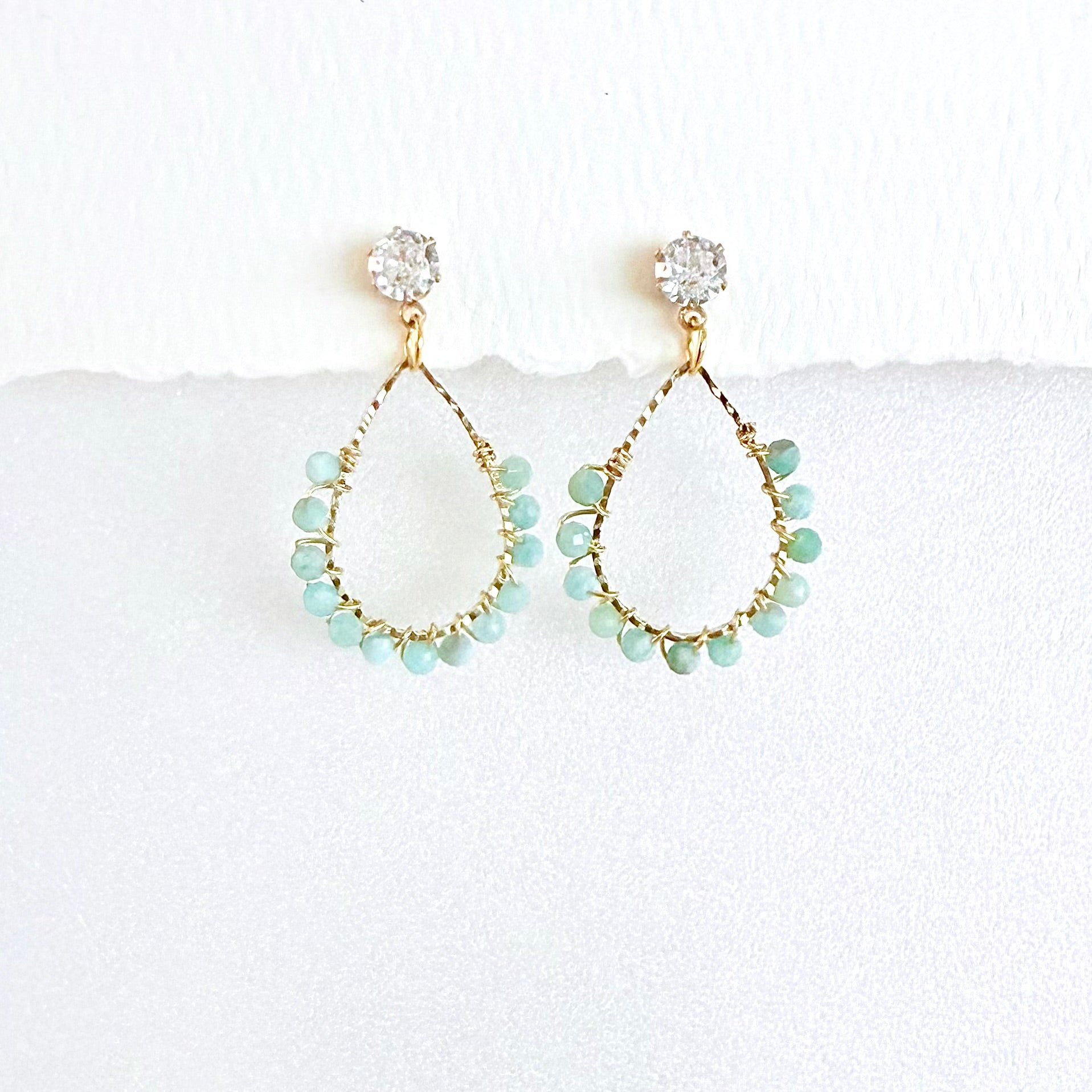 Gold teardrop earrings wrapped with Aquamarine beads on a white background by artist Julie Hamilton 