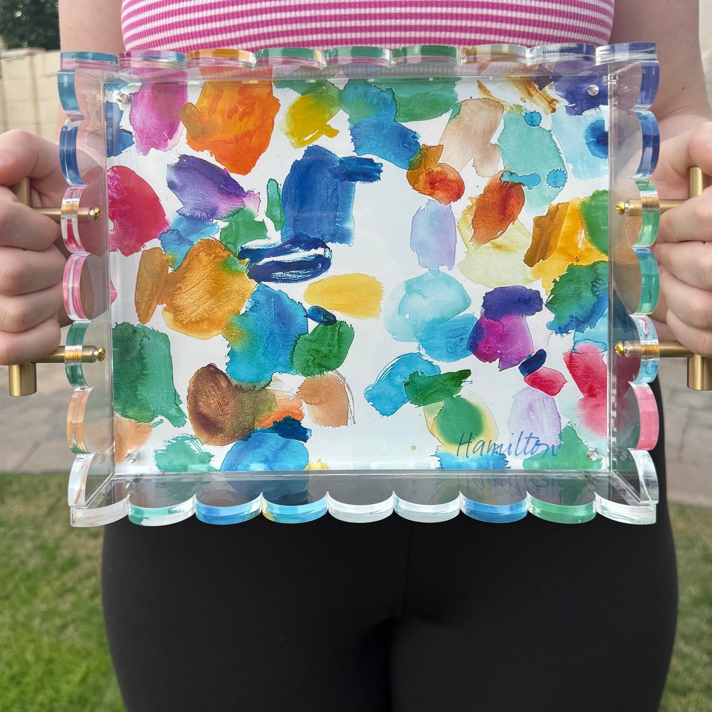 An 8” x 10” clear acrylic tray with colorful watercolor palette print bottom held by gold handles outside of phoenix Az studio