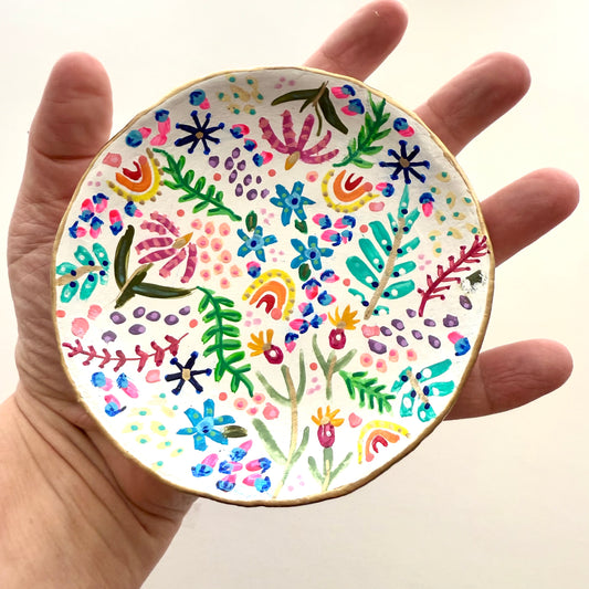 In my Hand I’m holding a small handmade clay plate with colorful floral patterns by Phoenix artist Julie Hamilton