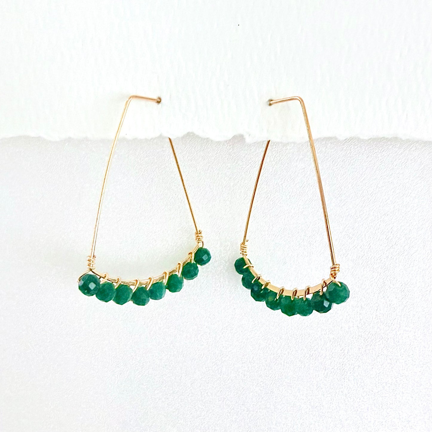 Gold hoop earrings with green beads on a white background by phoenix artist Julie Hamilton