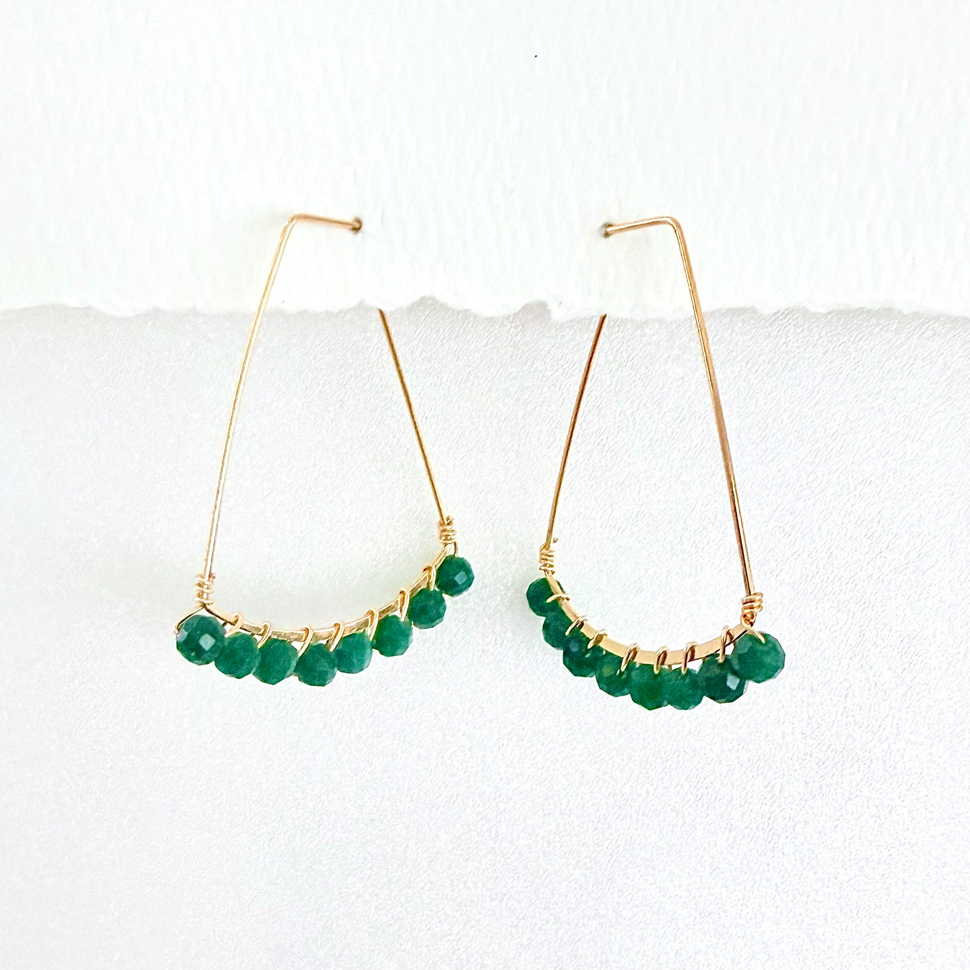 Gold hoop earrings with green beads on a white background by phoenix artist Julie Hamilton