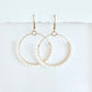 Gold hoop earrings wrapped with white beads on a white background by Phoenix artist Julie Hamilton