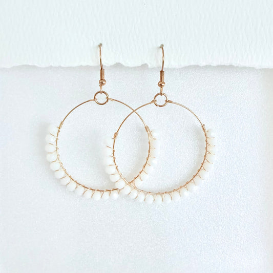 Gold hoop earrings wrapped with white beads on a white background by Phoenix artist Julie Hamilton