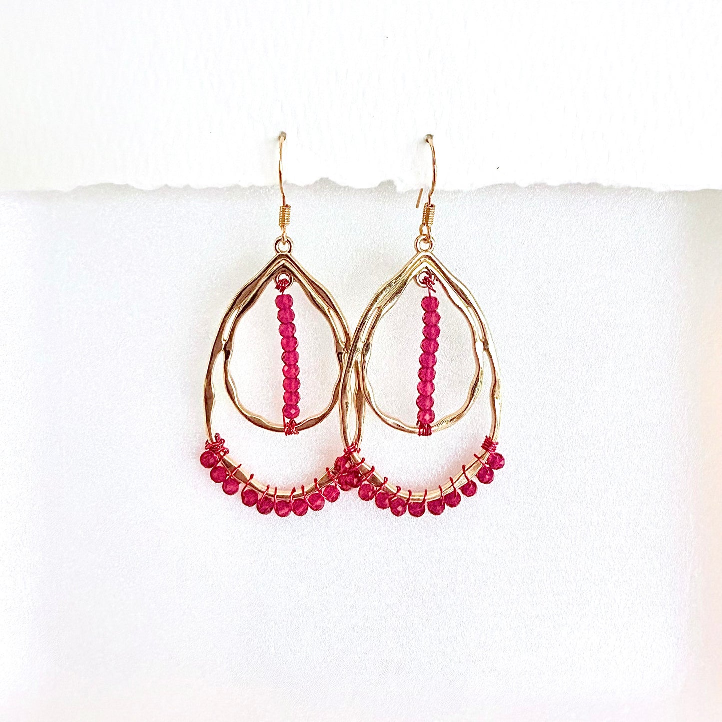 Gold hoop earrings with pink beads on a white background by Phoenix artist Julie Hamilton