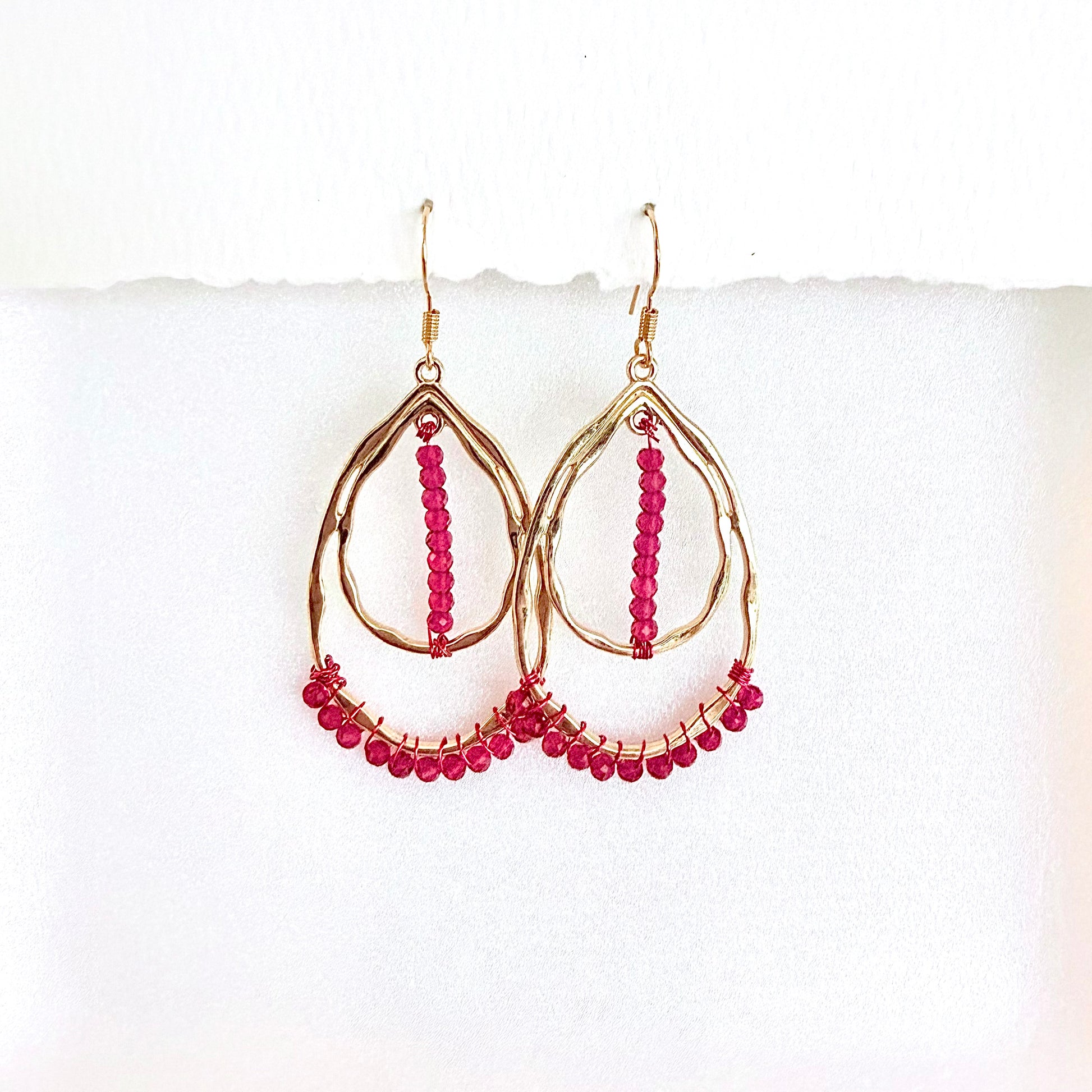 Gold hoop earrings with pink beads on a white background by Phoenix artist Julie Hamilton