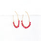 Gold hoop earrings with faceted pink beads on a white background by artist Julie Hamilton