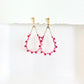 Pair of beaded earrings with pink and red beads on a white background by artist Julie Hamilton