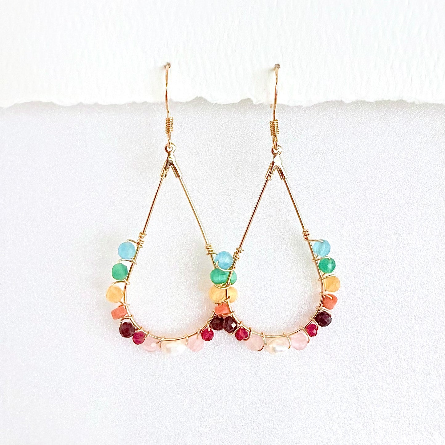 Gold hoop earrings with faceted rainbow beads on a white background by artist Julie Hamilton