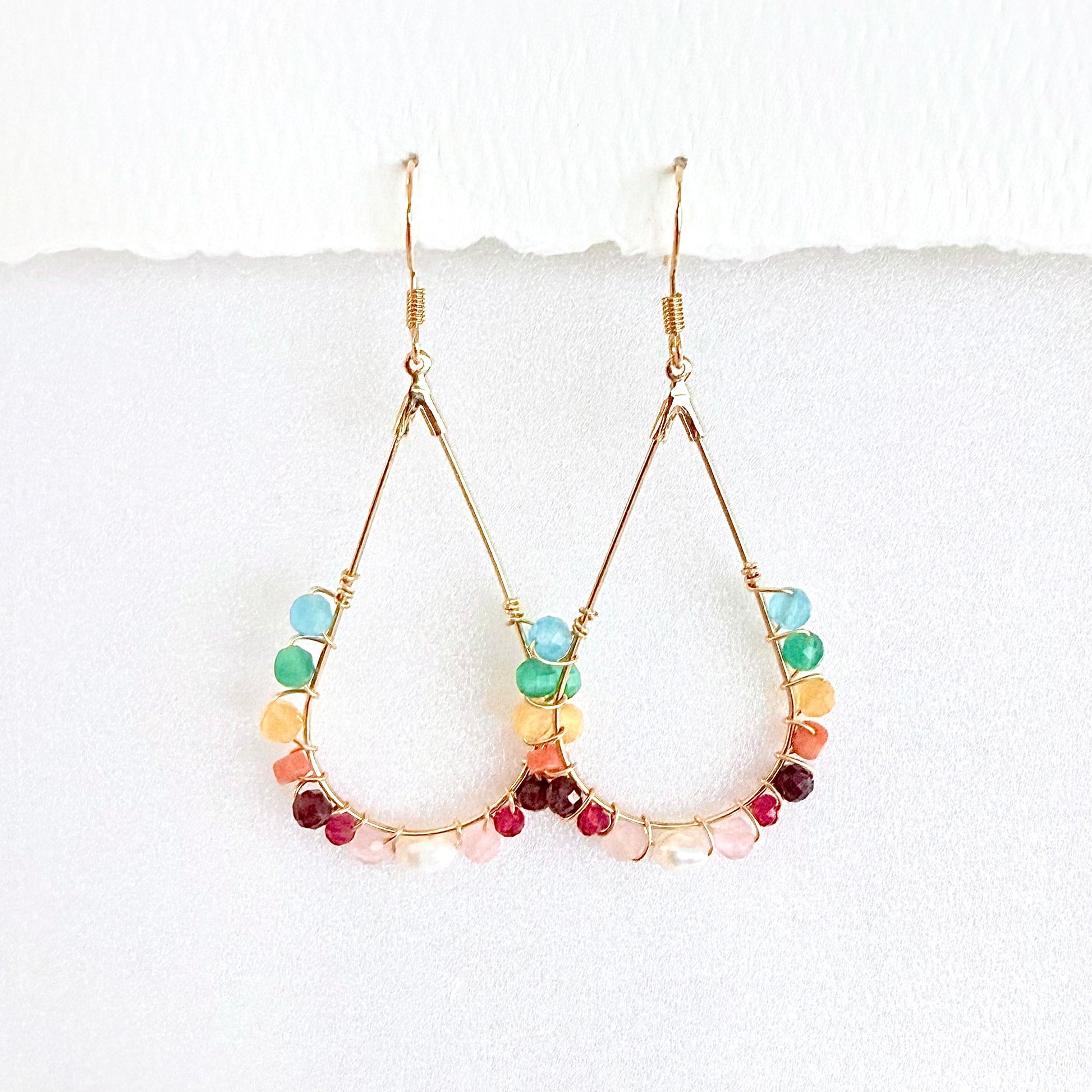 Gold hoop earrings with faceted rainbow beads on a white background by artist Julie Hamilton