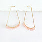 Gold hoop earrings with pale pink rose quartz beads on a white background by artist Julie Hamilton