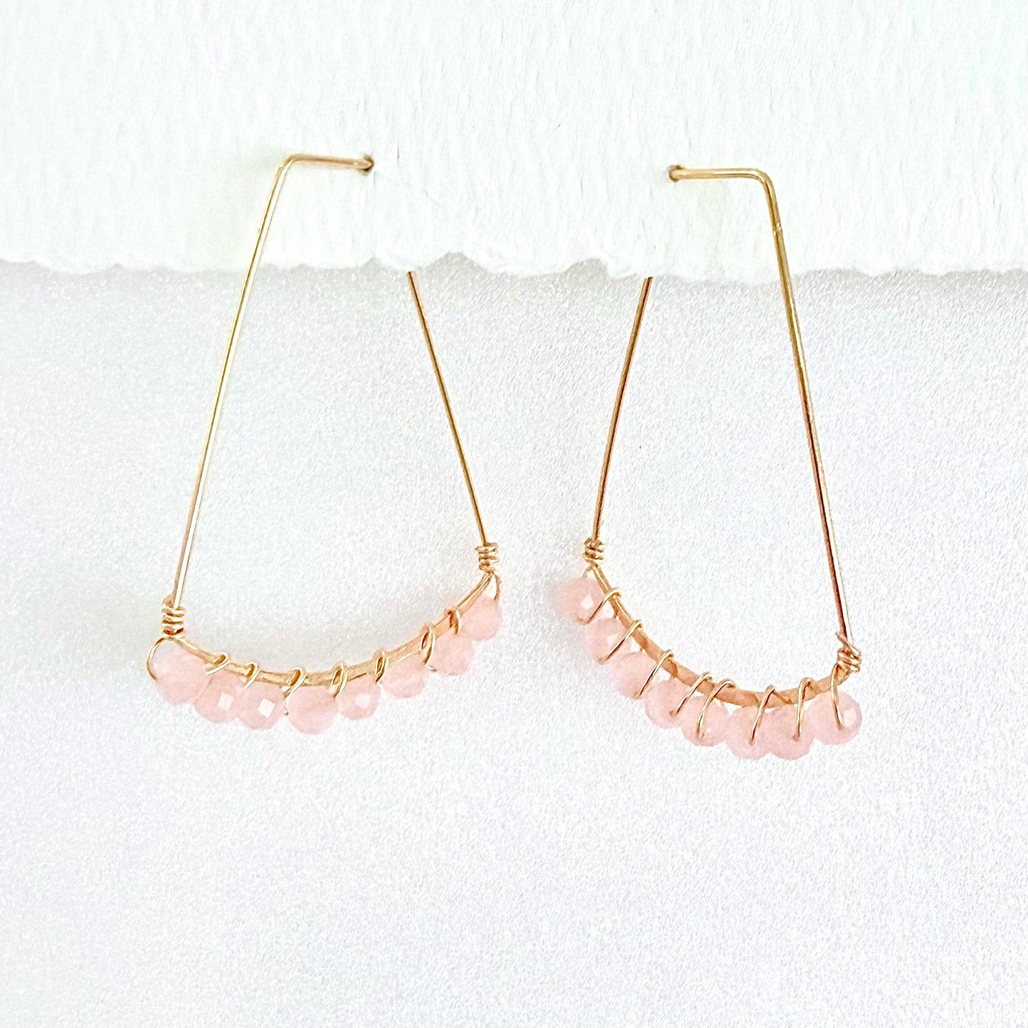 Gold hoop earrings with pale pink rose quartz beads on a white background by artist Julie Hamilton