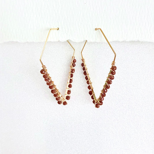 Pair of gold hoop earrings with sparkling brown sunstone beads on a white background by artist Julie Hamilton