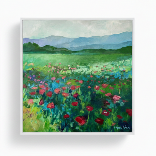 Framed painting of a colorful field with flowers and mountains
