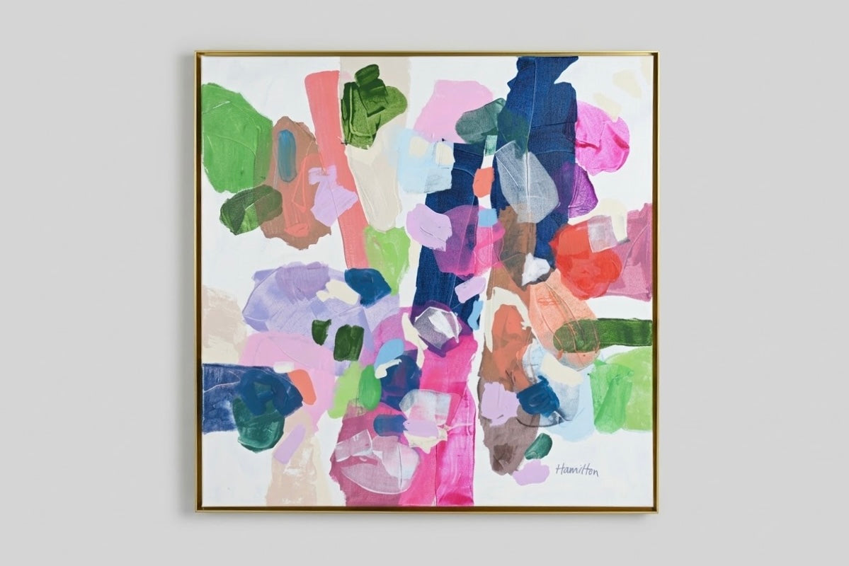 An abstract framed painting featuring a vibrant mix of brushstrokes in pink, green, blue, purple, orange, and beige on a white background, enclosed in a thin gold frame.