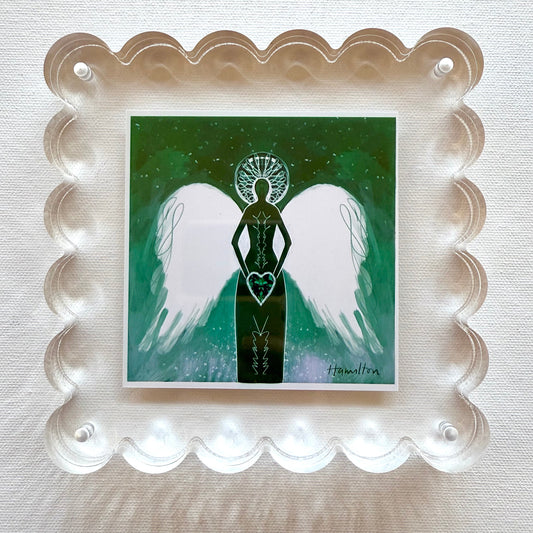 Framed artwork of an angel holding an emerald heart with white wings on a green background