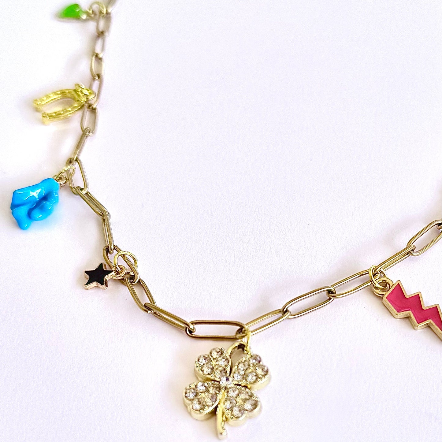Gold chain bracelet with various charms on a white background