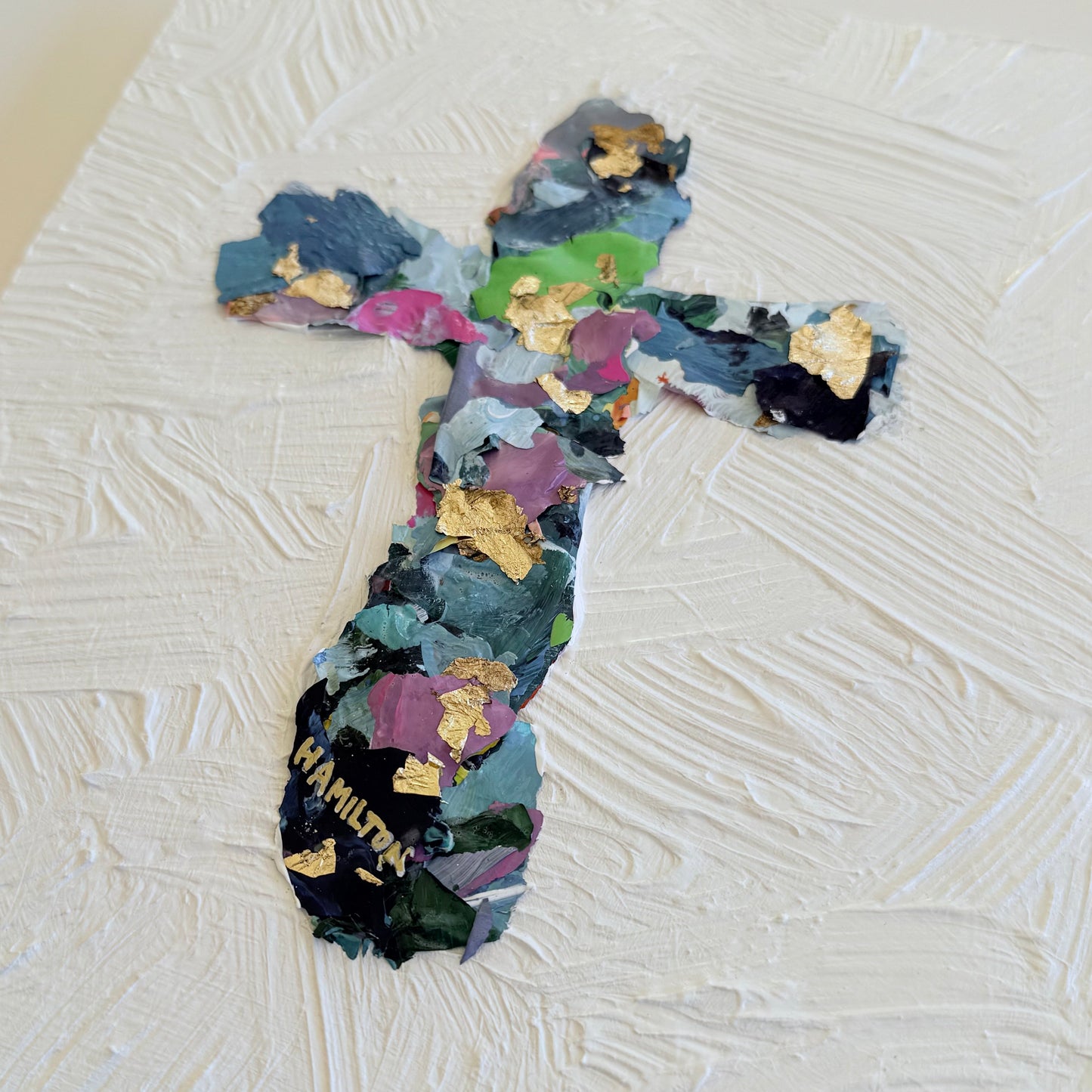 Colorful cross-shaped collage on a textured white canvas 