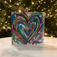 Colorful heart-shaped artwork on a glass panel with a Christmas tree in the background