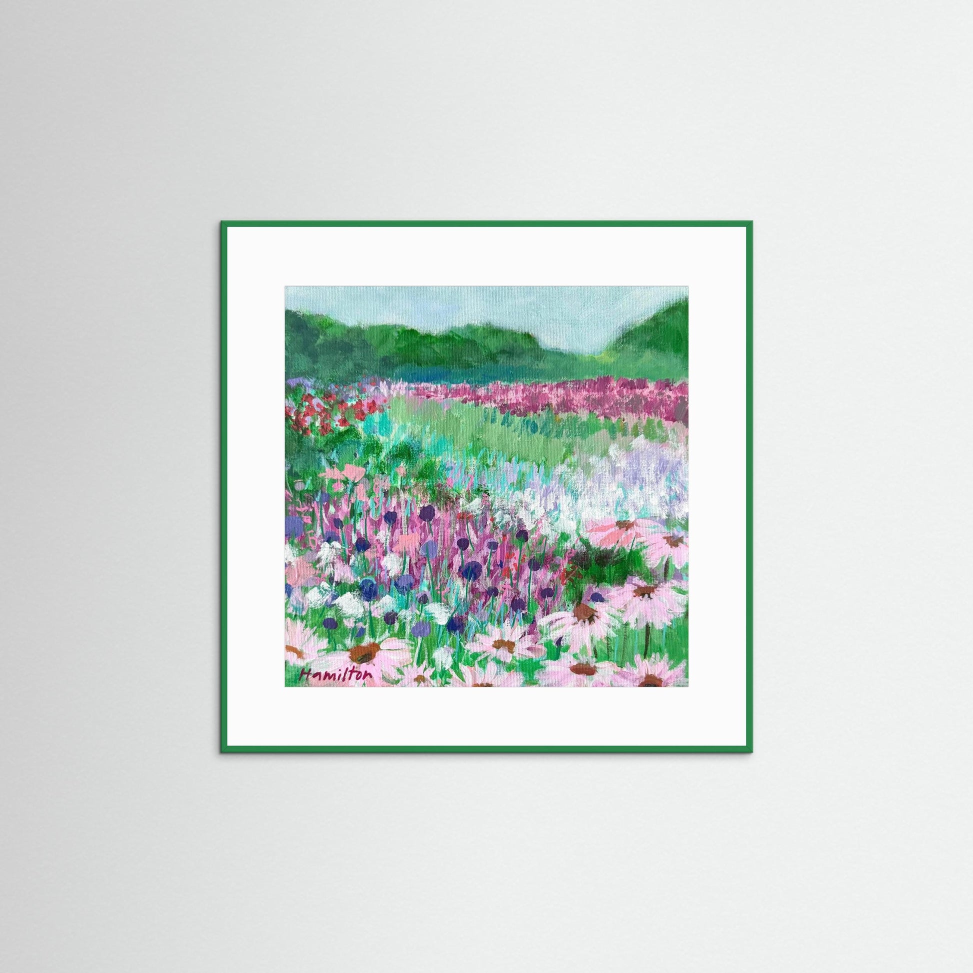 Framed art print of a colorful floral landscape on a white wall