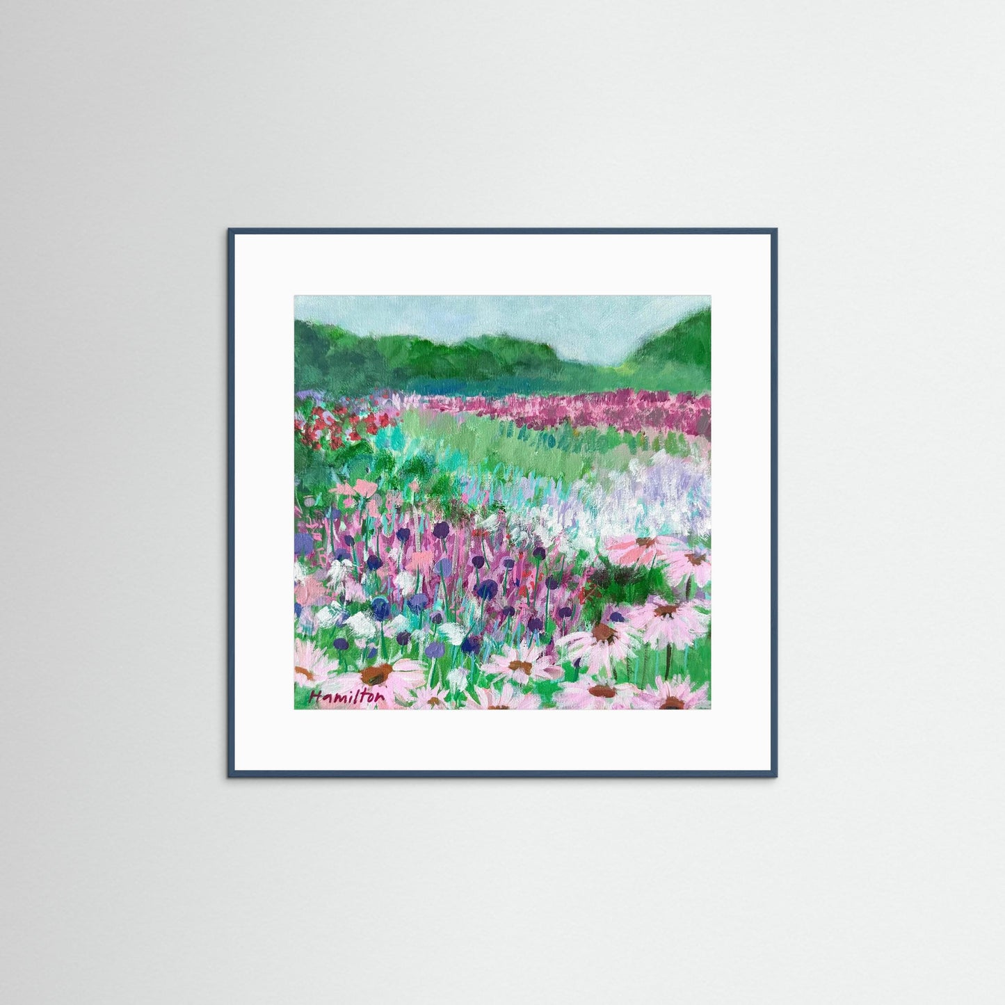 Framed art print of a colorful floral landscape on a white wall