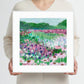 Person holding a framed print of a painting of a colorful floral field
