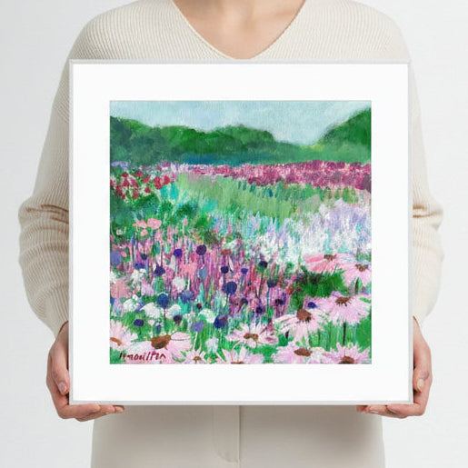 Person holding a framed print of a painting of a colorful floral field