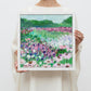 Framed painting of a colorful field of flowers with a mountainous background.