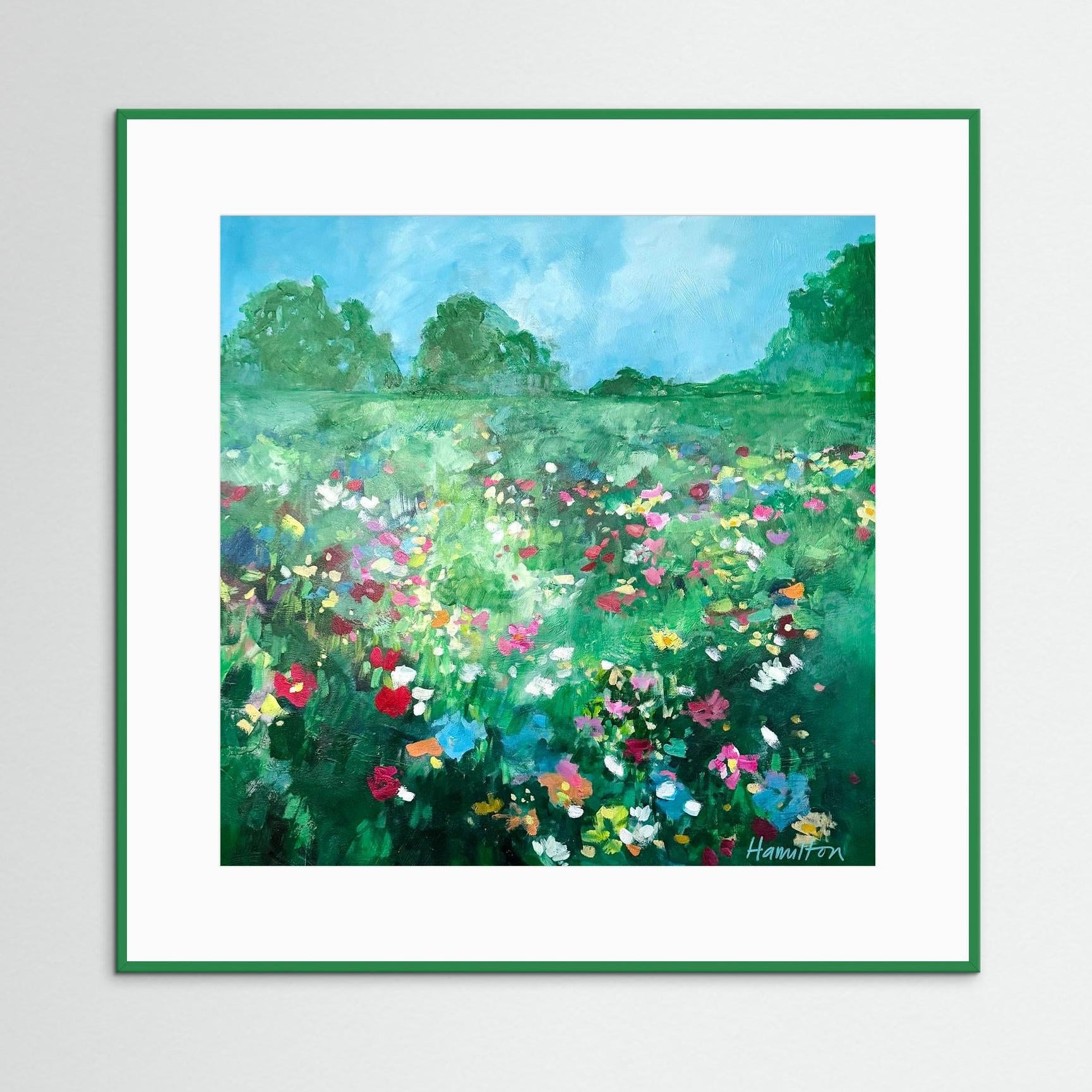 green Framed painting of a colorful garden scene on a white wall