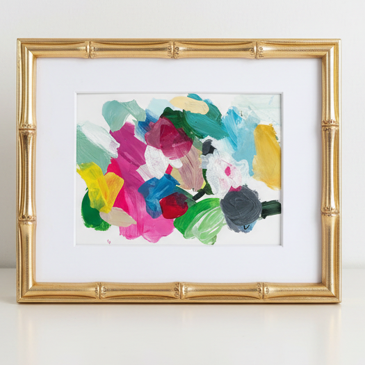 Colorful abstract painting in a gold frame on a white background